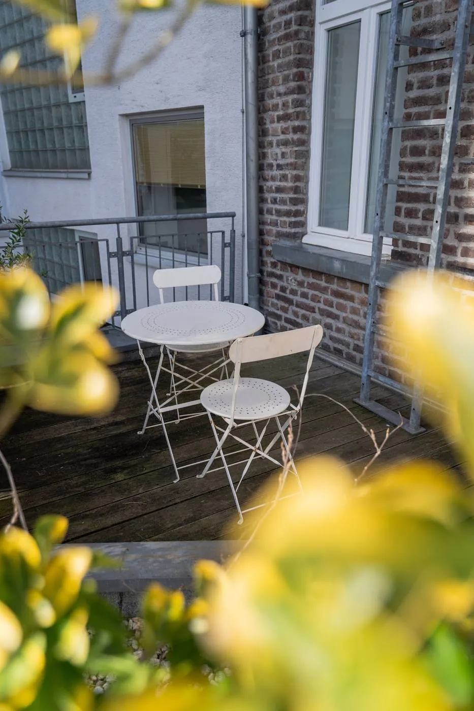 Terrasse mit weißem Bistro-Set zwischen Backsteinfassade und Geländer, Deluxe Zimmer im Maison Marsil